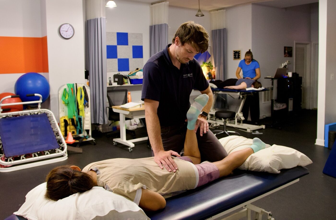 A Sports & Ortho physical therapist performing hands-on manual therapy on a patient's leg