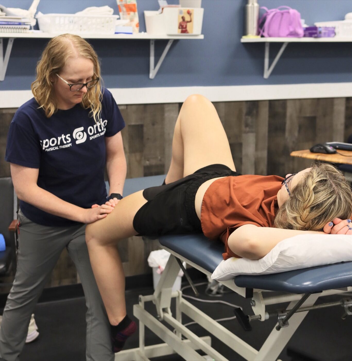 A Sports & Ortho therapist performing hands-on assessment of a patient's leg