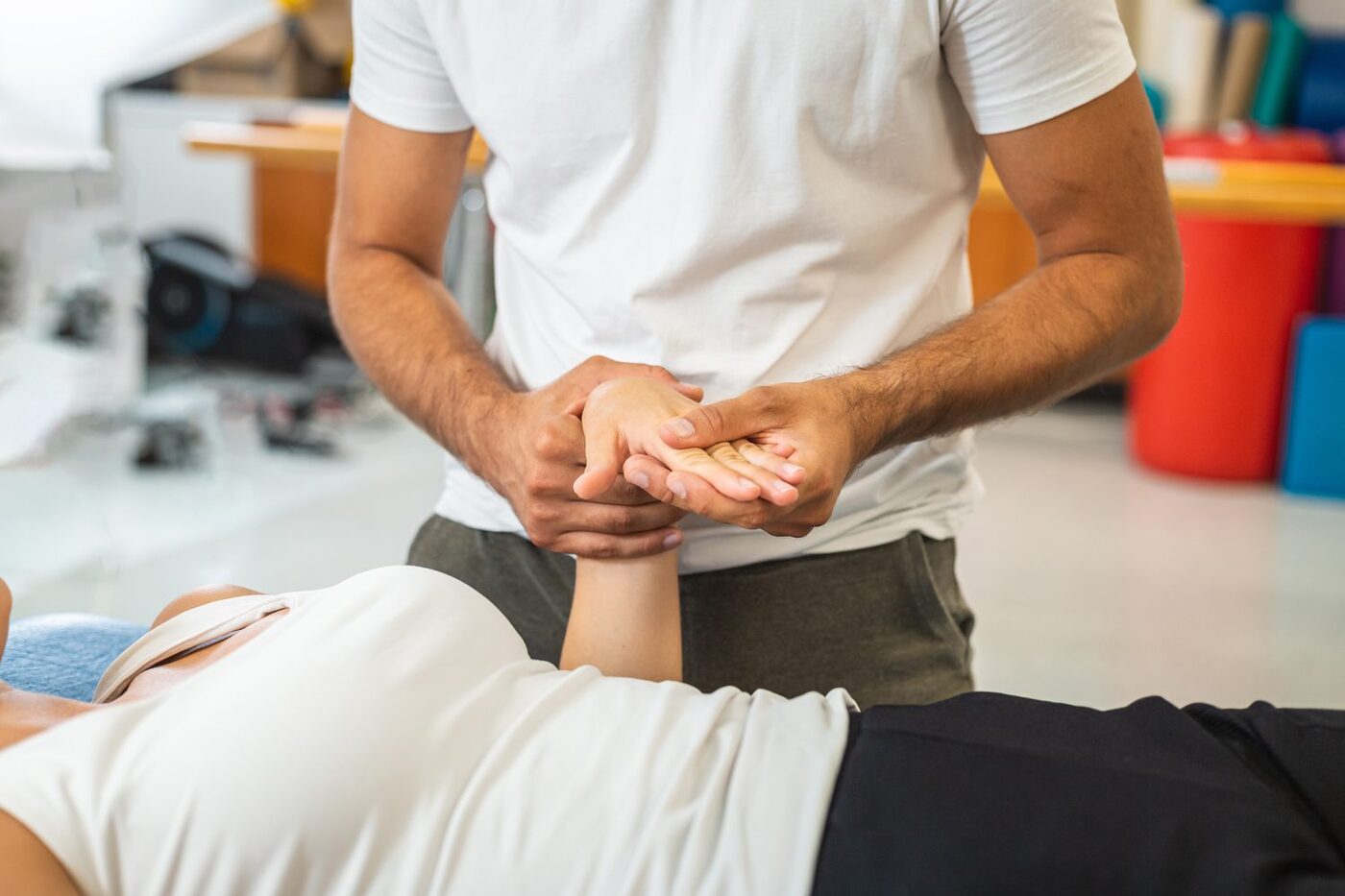 A therapist mobilizing a patient's hand and wrist during a treatment session