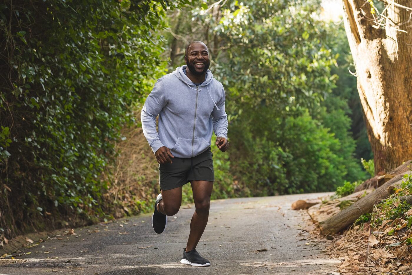 A runner mid-stride on a tree-lined path, smiling