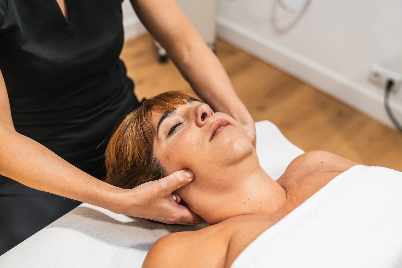 A therapist performing gentle hands-on treatment at a patient's jaw